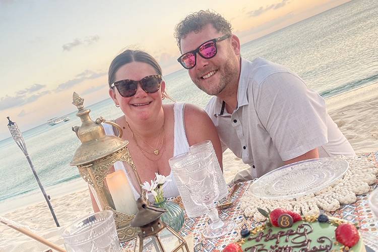 couple sitting on beach at table set for picnic