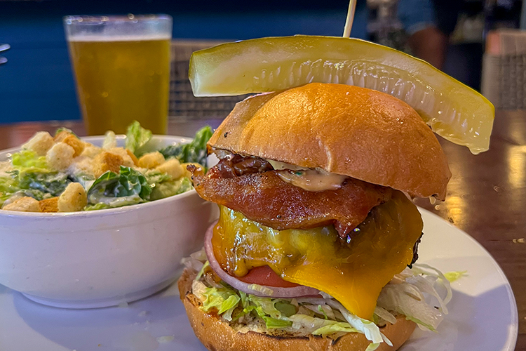 burger with a pick through it and beer in background
