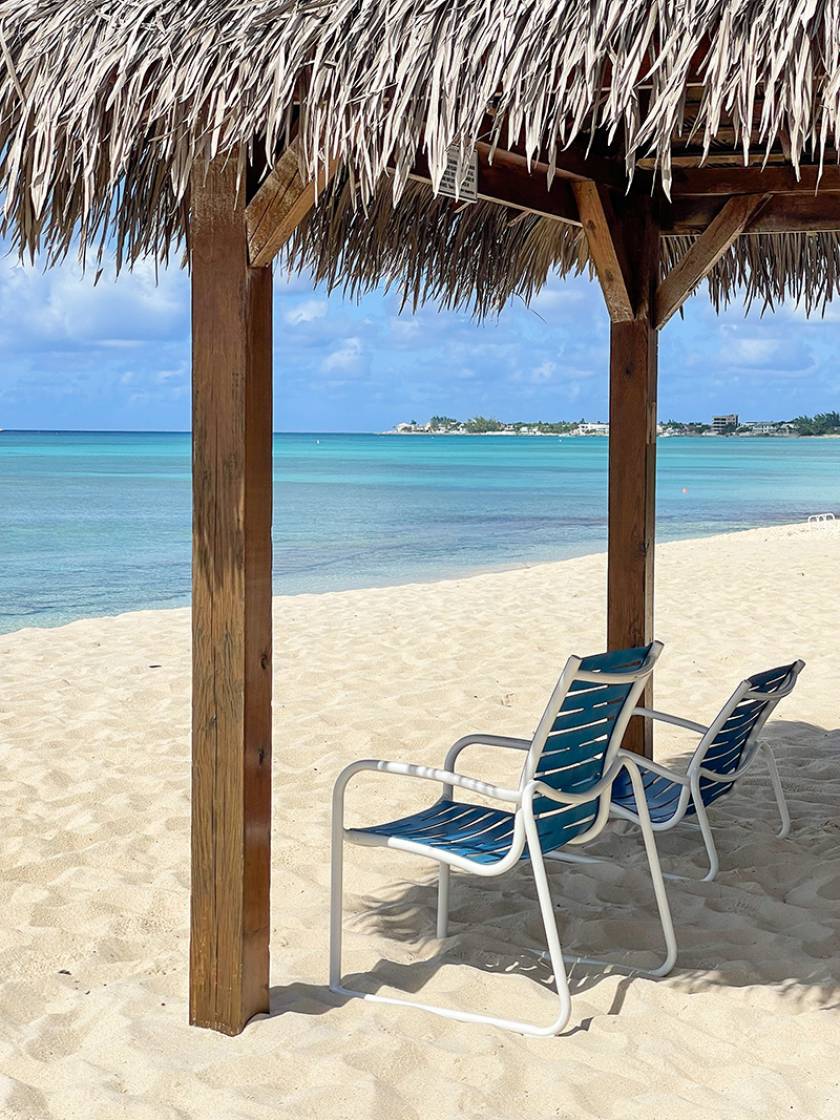 chairs under a tiki hut on beach